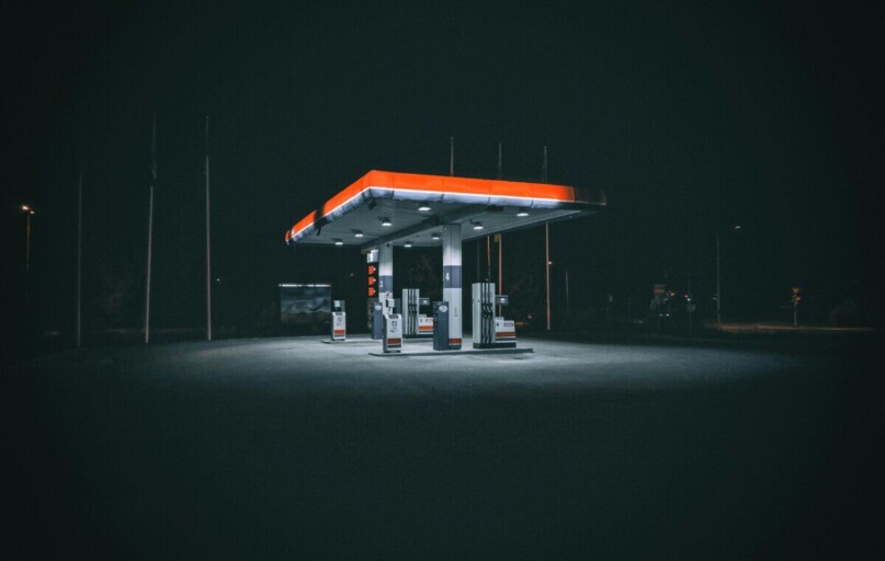 An isolated and illuminated gas station at night, highlighting urban solitude under a dark sky.