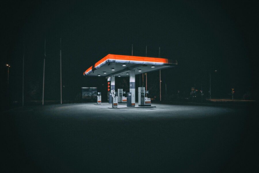 An isolated and illuminated gas station at night, highlighting urban solitude under a dark sky.