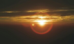 Beautiful sunset with vibrant sun and clouds over Campo dei Fiori, Italy.