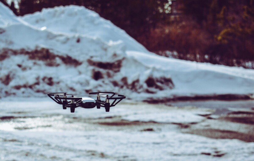 A drone hovering over a snowy terrain with blurred winter background.