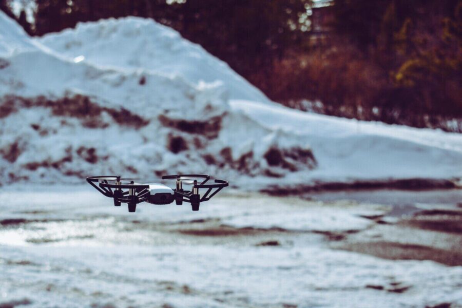 A drone hovering over a snowy terrain with blurred winter background.