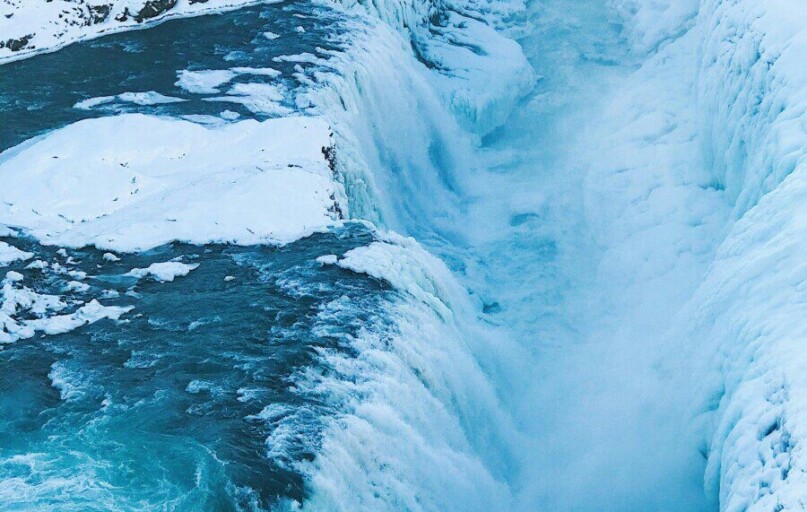Stunning view of a frozen waterfall cascading through a snowy Icelandic gorge, capturing winter's icy beauty.