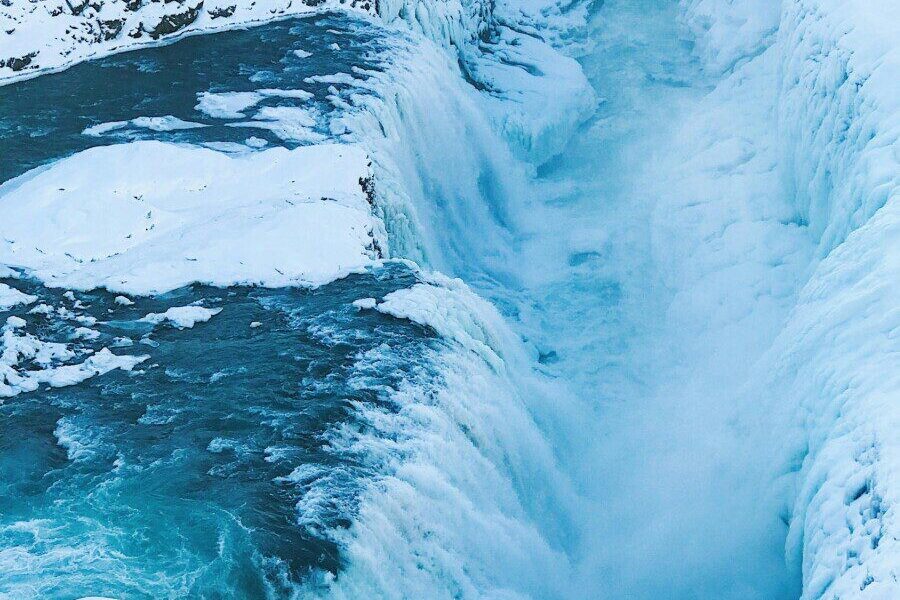 Stunning view of a frozen waterfall cascading through a snowy Icelandic gorge, capturing winter's icy beauty.