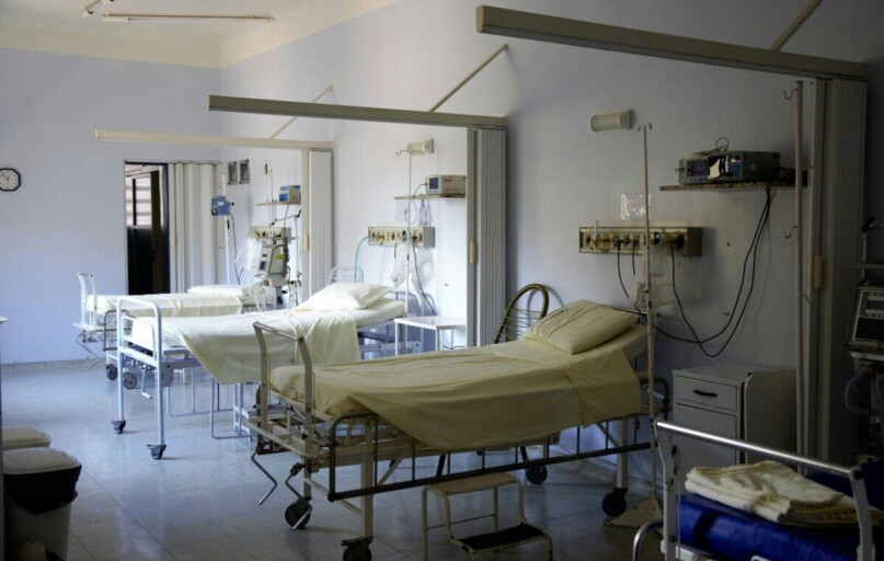 Spacious hospital room with several empty beds and medical equipment, emphasizing healthcare and hygiene.