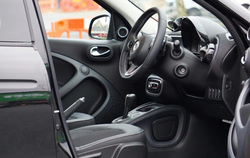 A sleek car interior showcasing the steering wheel and dashboard through an open door.