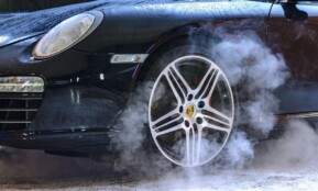 Close-up of a luxury car wheel with steam and water droplets, showcasing power and style.
