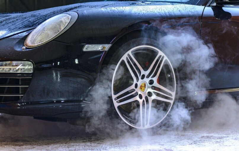 Close-up of a luxury car wheel with steam and water droplets, showcasing power and style.