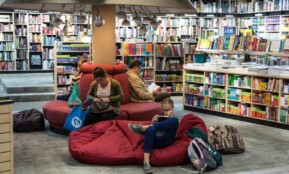 A welcoming library space with people relaxing and reading on comfortable seating.
