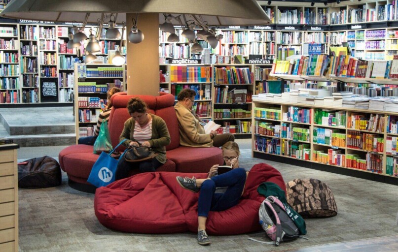 A welcoming library space with people relaxing and reading on comfortable seating.