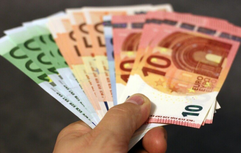 A fan of euro banknotes in various denominations held in a hand.