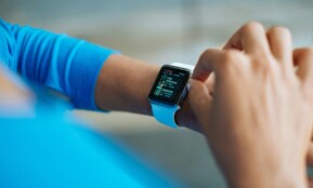 Person interacting with a smartwatch, showing a fitness application on the screen.