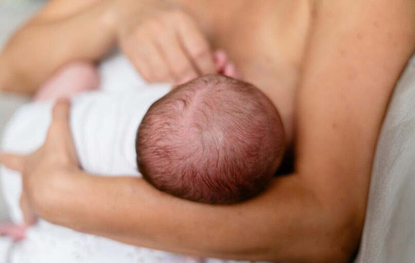 Tender moment of a mother breastfeeding her newborn, highlighting love and bonding.
