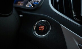 Close-up image of a car's engine start stop button on the dashboard.