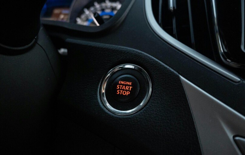 Close-up image of a car's engine start stop button on the dashboard.