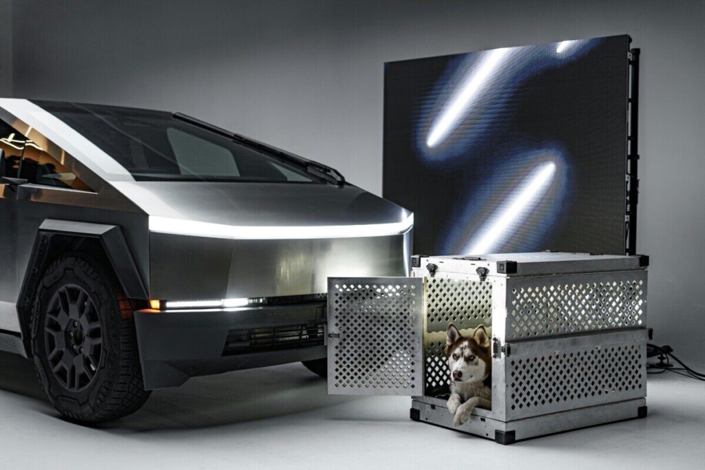Alaskan Malamute in a durable metal crate beside a futuristic vehicle.