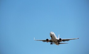 Virgin Australia aircraft captured mid-landing against a clear blue sky at Melbourne Airport.