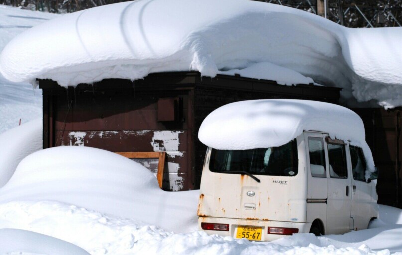 Snow-covered van and building in Nagano Prefecture, Japan, during winter.