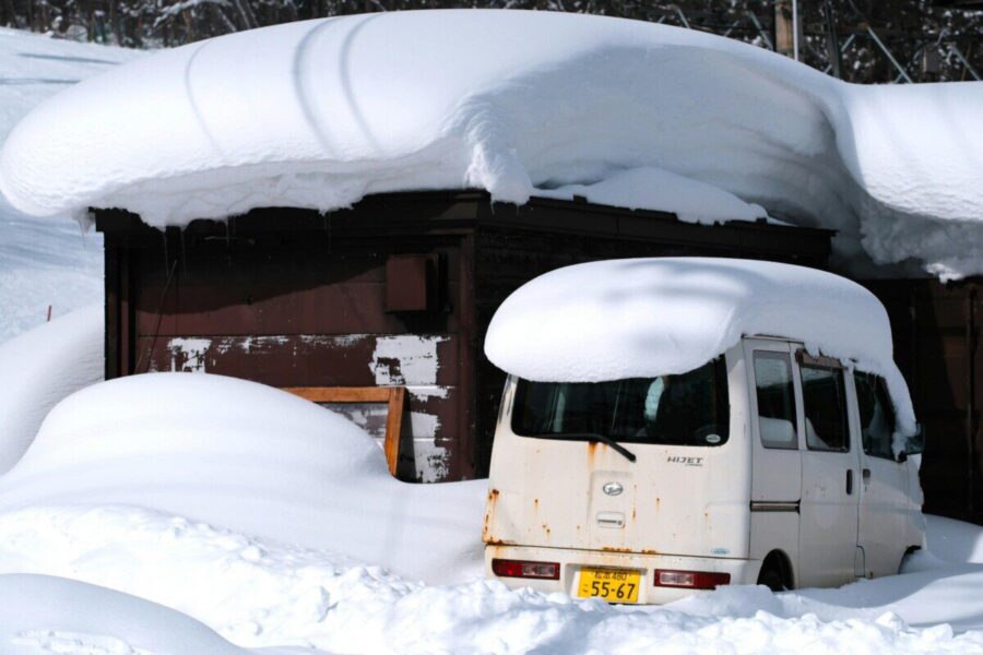 Snow-covered van and building in Nagano Prefecture, Japan, during winter.