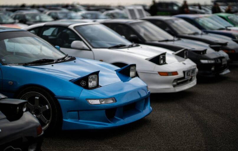 Toyota MR2 sports cars with popup headlights showcased at a car meet in England.