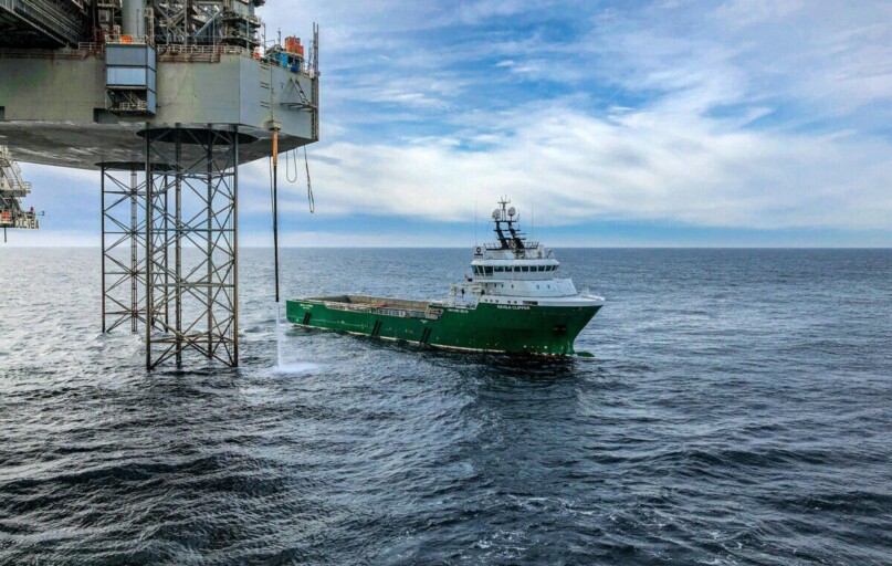Supply vessel approaching offshore oil platform in Danish waters, showcasing maritime industry.