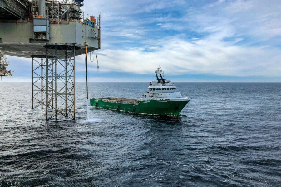 Supply vessel approaching offshore oil platform in Danish waters, showcasing maritime industry.