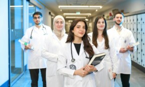 Group of diverse medical students wearing lab coats in university corridor, representing future healthcare professionals.