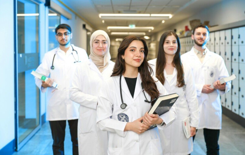 Group of diverse medical students wearing lab coats in university corridor, representing future healthcare professionals.