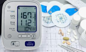 A close-up shot of medical equipment including blood pressure monitor and pills on an ECG graph.