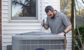 A technician inspects an outdoor HVAC unit for maintenance.