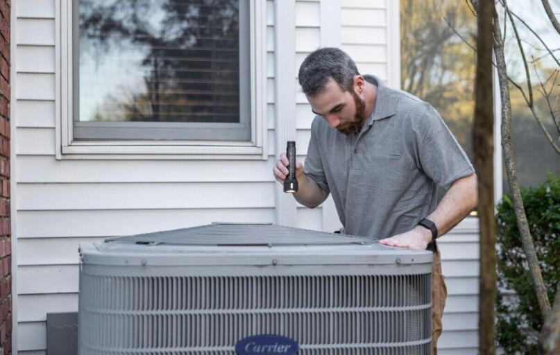 A technician inspects an outdoor HVAC unit for maintenance.