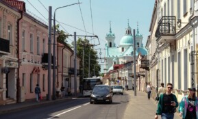 Bustling city street with classic architecture and a distant church under a clear sky.
