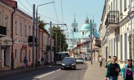 Bustling city street with classic architecture and a distant church under a clear sky.