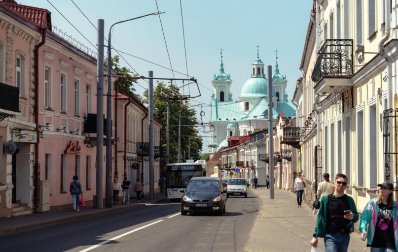 Bustling city street with classic architecture and a distant church under a clear sky.
