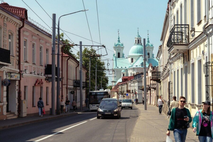 Bustling city street with classic architecture and a distant church under a clear sky.