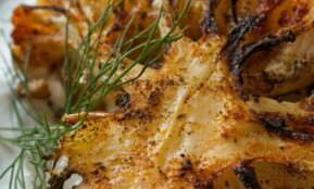 Close-up of grilled cauliflower seasoned with dill on a white plate.