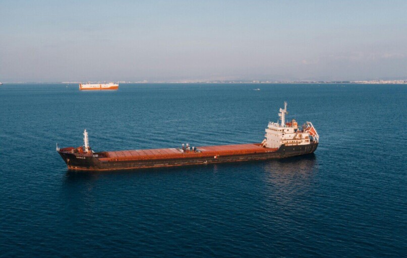 Aerial view of a cargo ship sailing in the open sea under clear skies, showcasing maritime transport.