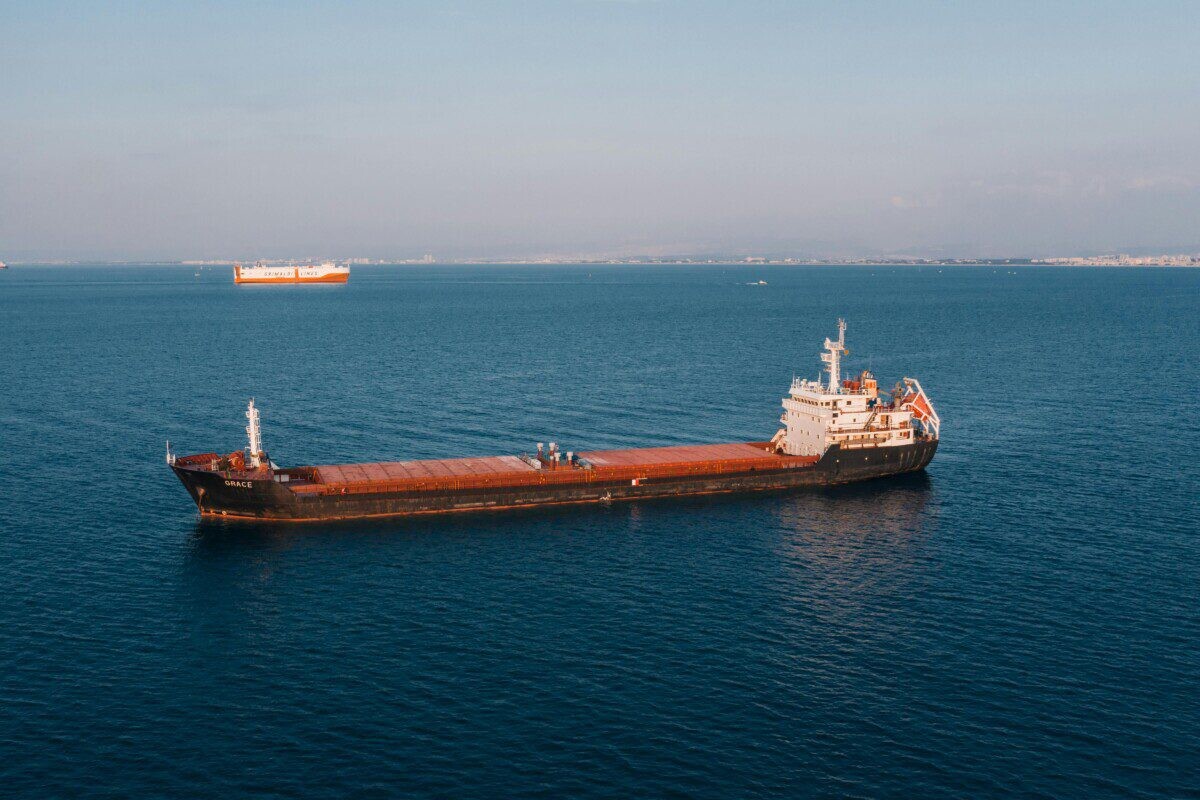 Aerial view of a cargo ship sailing in the open sea under clear skies, showcasing maritime transport.