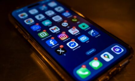 Smartphone screen displaying social media app notifications in a dimly lit setting.