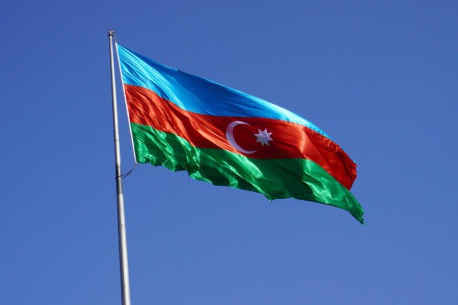 The national flag of Azerbaijan waves against a clear blue sky, symbolizing national pride.