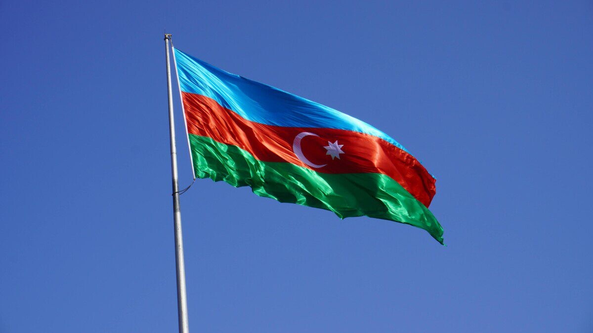 The national flag of Azerbaijan waves against a clear blue sky, symbolizing national pride.