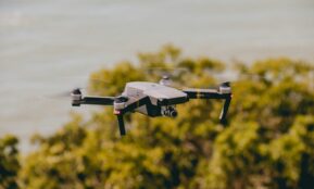 Aerial view of a drone flying over lush greenery and water, capturing stunning outdoor scenes.