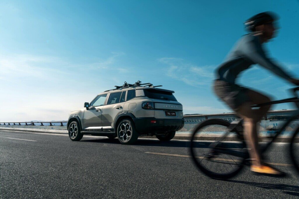 Modern SUV with bike rack cruised by cyclist on a sunny Georgia highway, highlighting outdoor adventure.