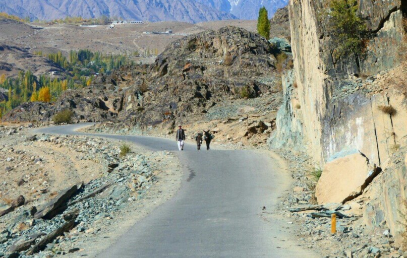 Explorers on a winding road in the rugged Gilgit-Baltistan landscape.