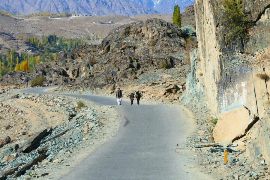 Explorers on a winding road in the rugged Gilgit-Baltistan landscape.