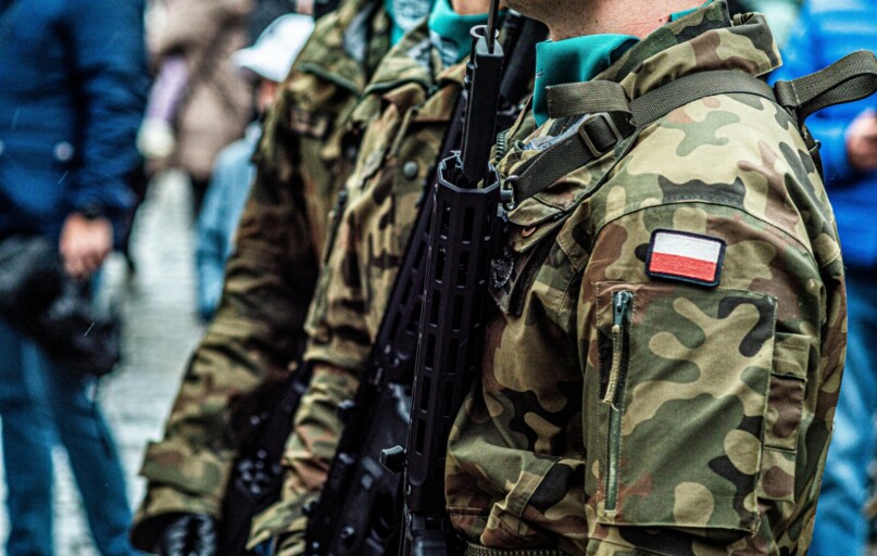 Close-up of Polish soldiers in camouflaged uniforms standing in line during a public event.