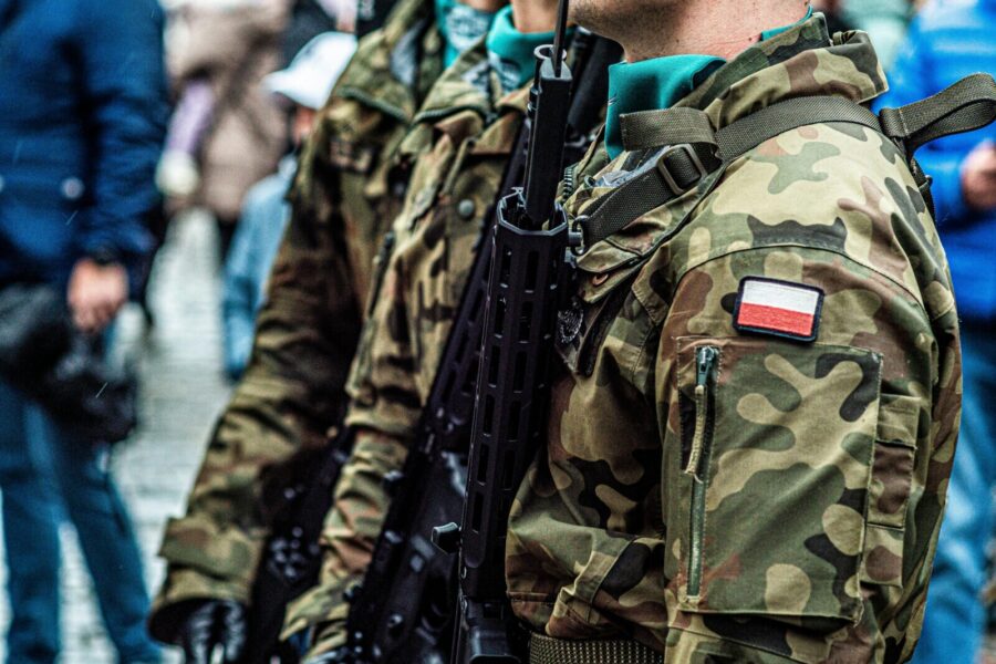 Close-up of Polish soldiers in camouflaged uniforms standing in line during a public event.