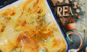 A rich and creamy potato gratin freshly baked, golden and crispy in a ceramic dish.