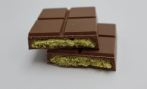 Close-up of a milk chocolate bar with pistachio filling, showcasing its delectable texture.