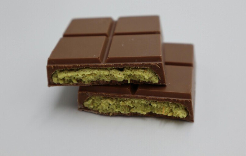 Close-up of a milk chocolate bar with pistachio filling, showcasing its delectable texture.