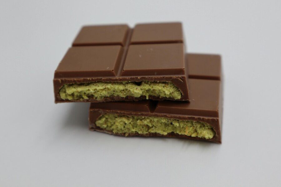 Close-up of a milk chocolate bar with pistachio filling, showcasing its delectable texture.
